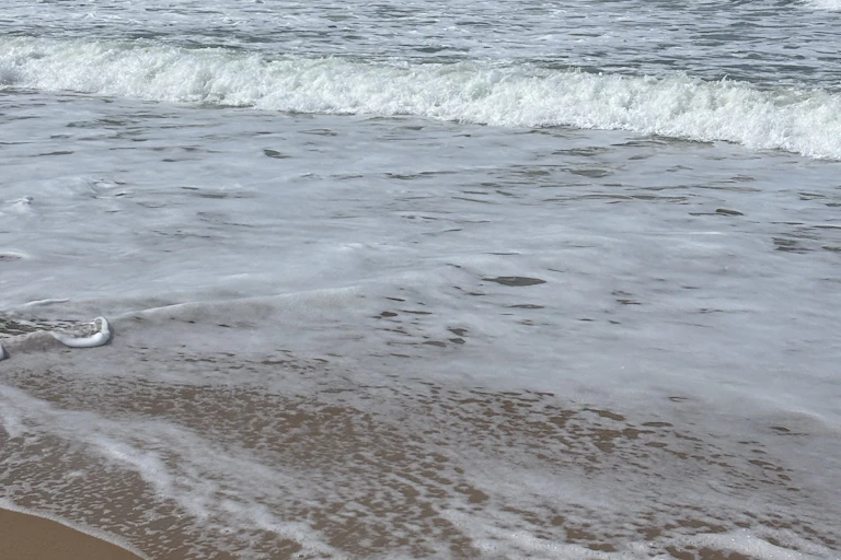 Two waves in the ocean breaking on the sand and creating foam