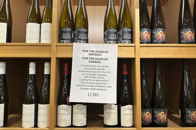 Rows of wine bottles are displayed on shelves with a sign that say U.S. products are no longer available at this Canadian store