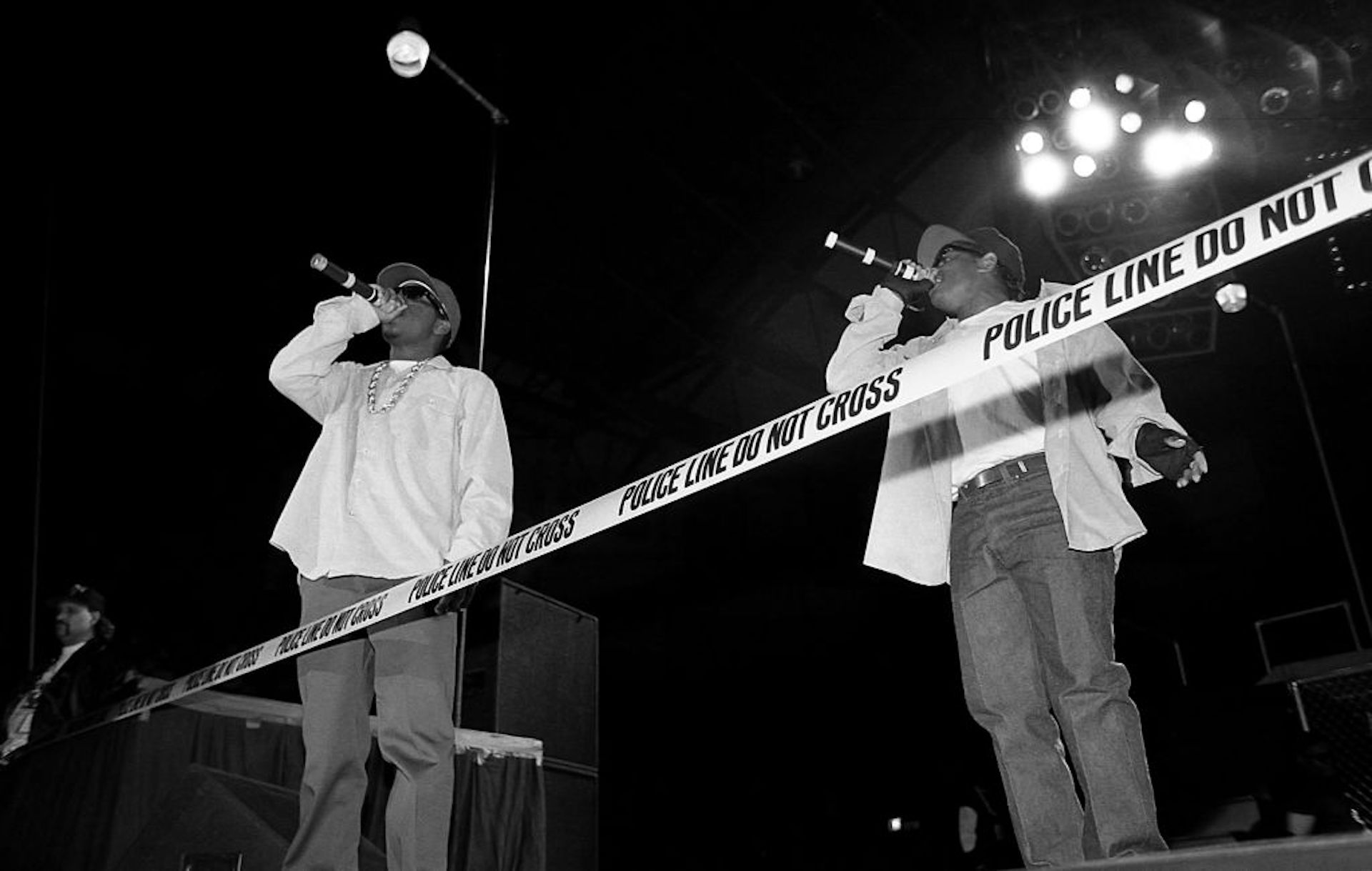 Black-and-white photo of two rappers performing on a stage.