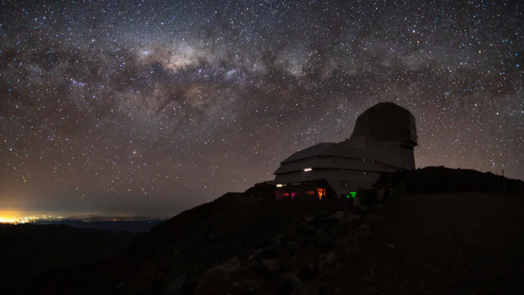 Observatory dome on a hill silhouetted against night sky with Milky Way streaming across it.