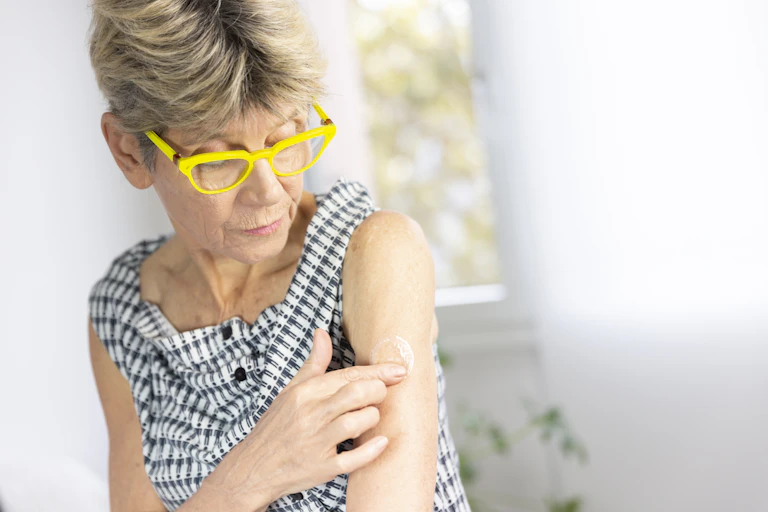 Woman applies clear patch to her arm.