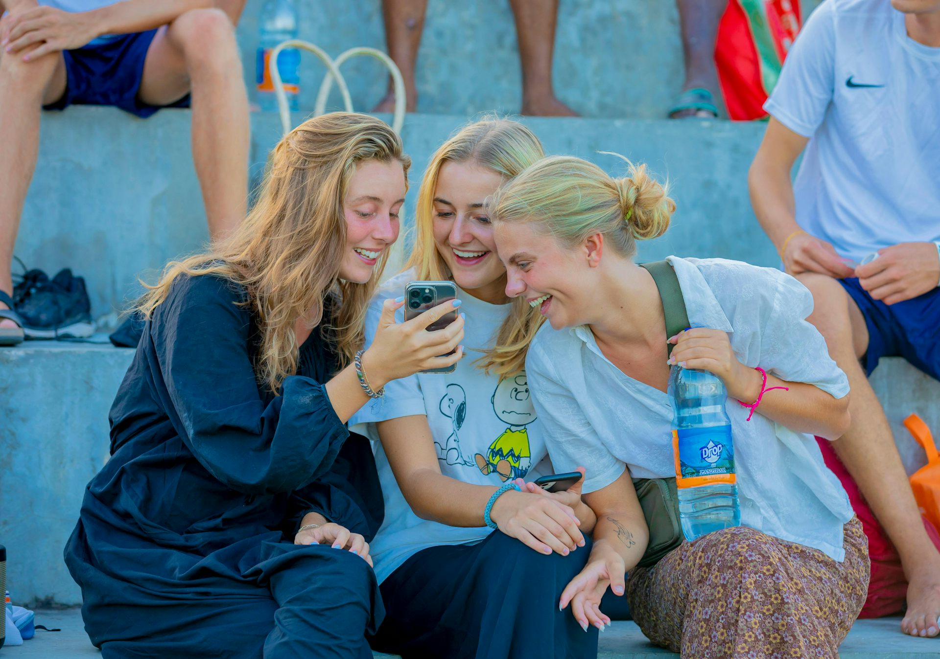 Three women sharing a joke looking at a phone screen.