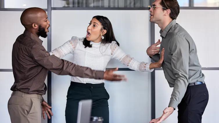 Two men and a woman having a tense argument at work