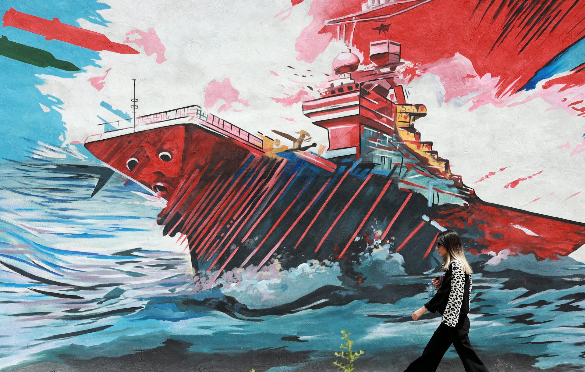 An Iranian walks next to an anti-US mural in a street in Tehran.
