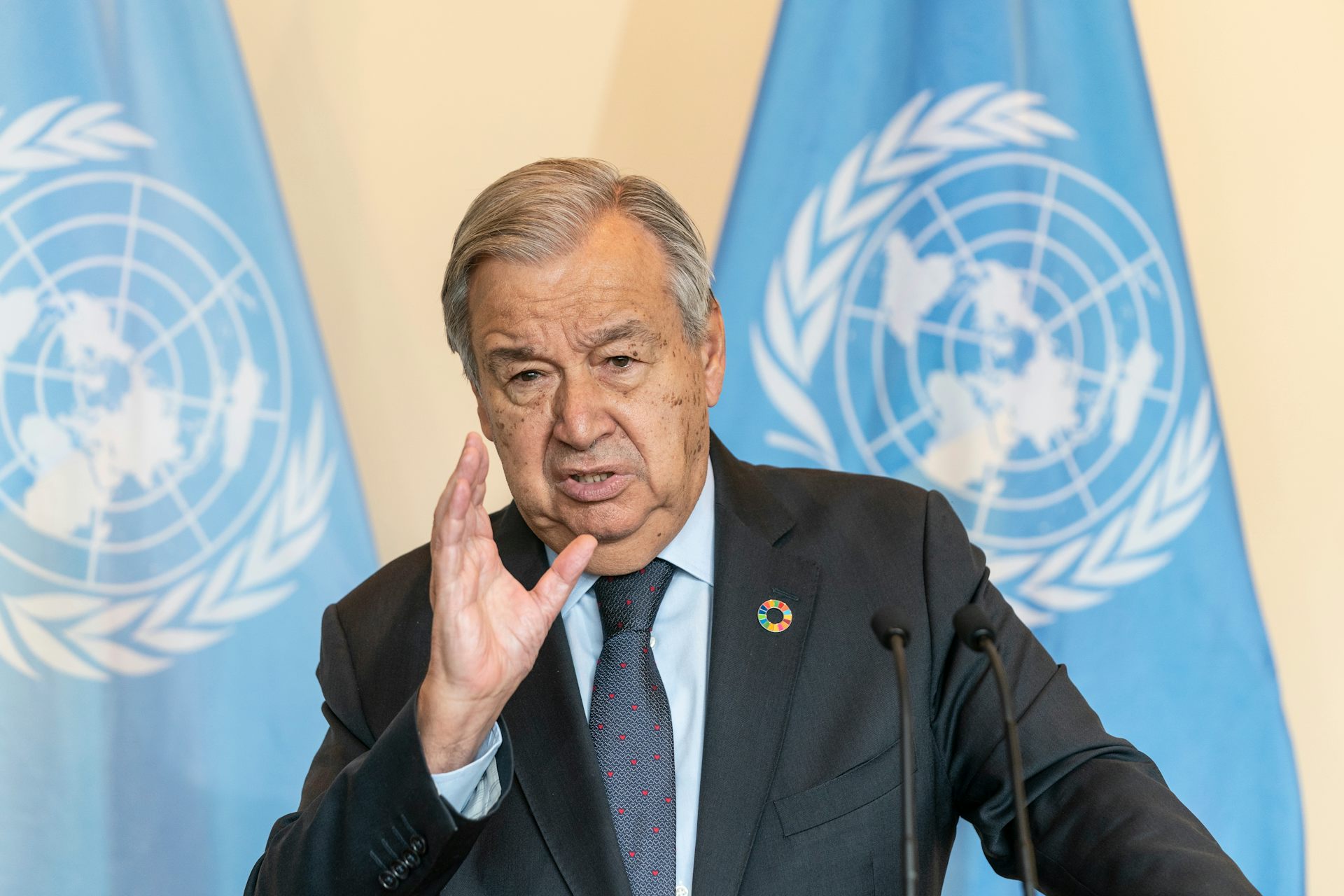 Un hombre con banderas de la ONU a su espalda.