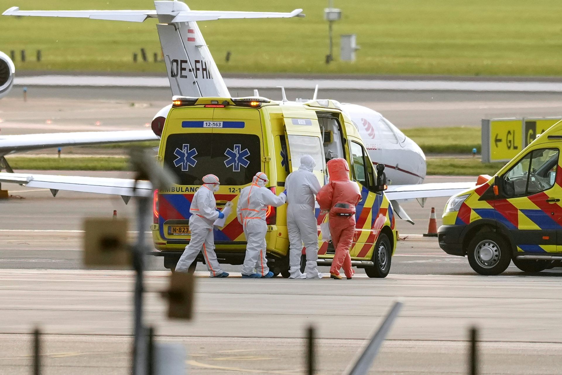 Du personnel médical est agglutiné devant un véhicule d'urgence sur une piste d'atterrissage