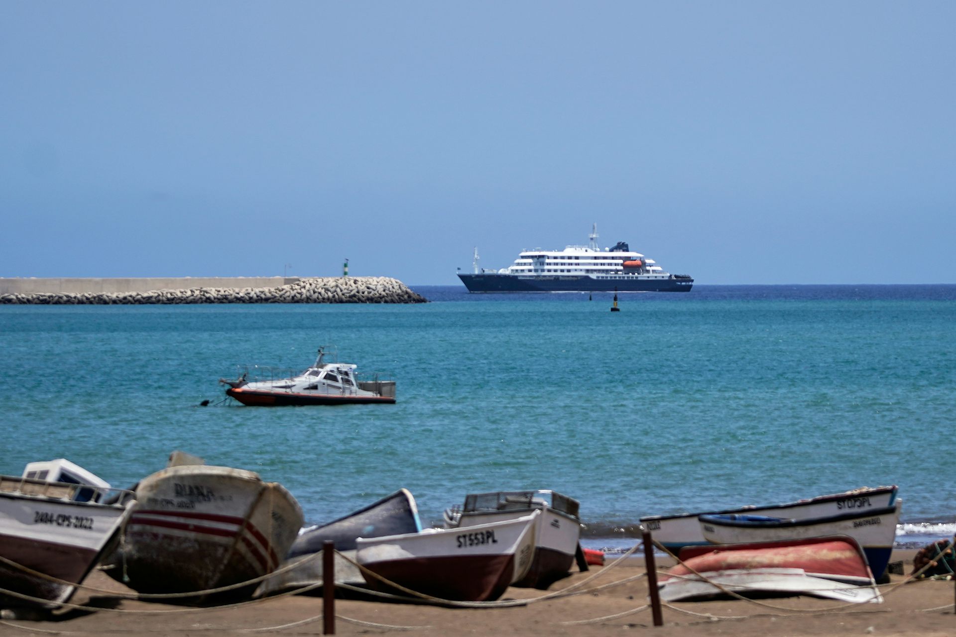 A boat is seen from a shore littered with various watercraft