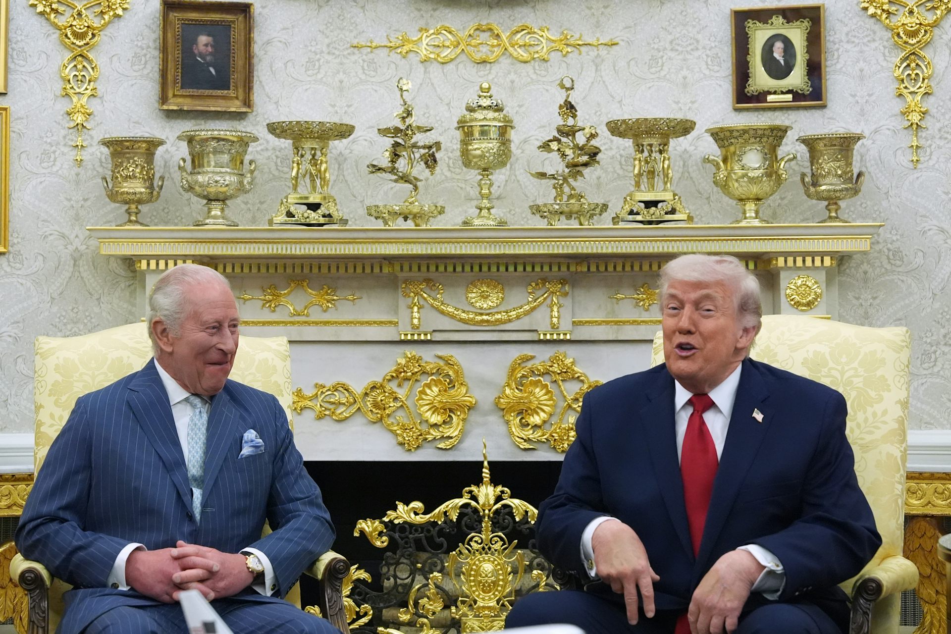 Two older men sit in a garishly gilded office.