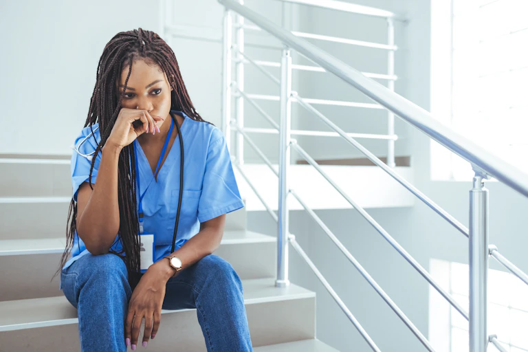 Upset female nurse sitting on hospital stairs