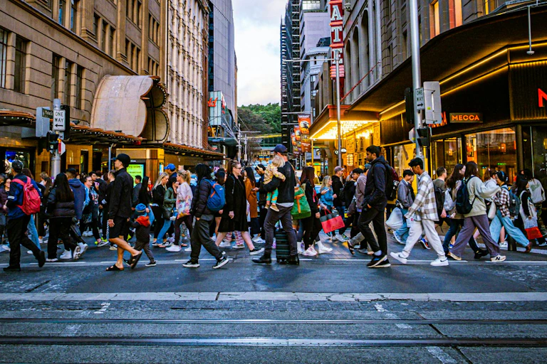 A crowd of people cross the street in the centre of Sydney