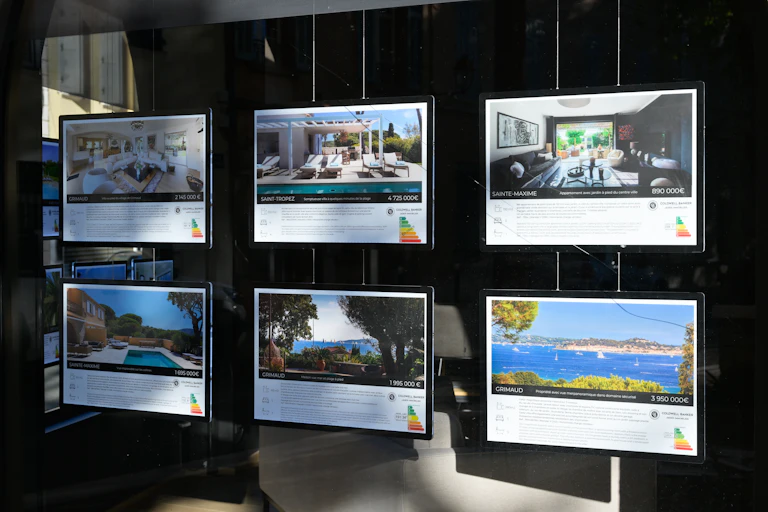 une vitrine d'agence immobilière avec des annonces d'appartements luxueux à Saint Tropez Sainte Maxime Grimaud....