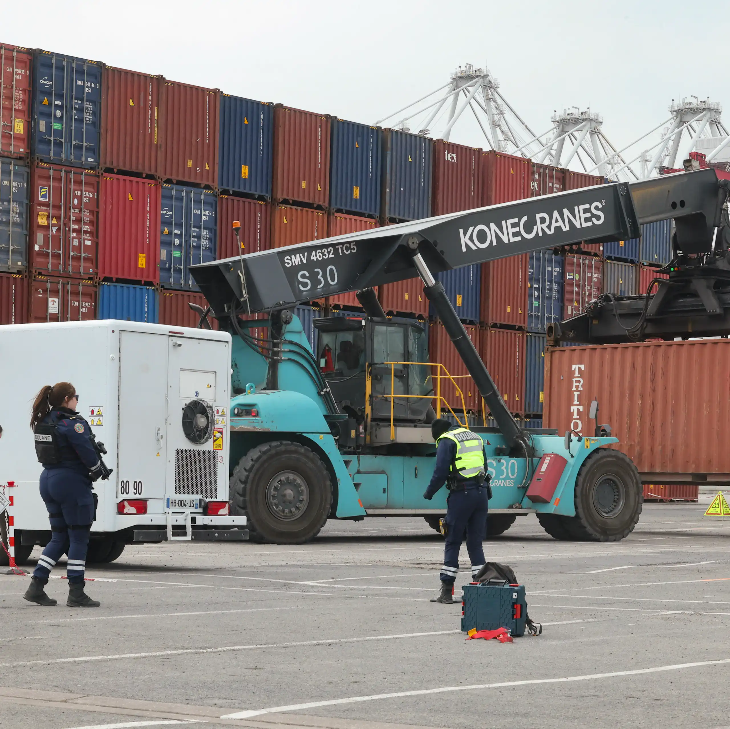 Sur les docks de Dunkerque, des douaniers inspectent un conteneur.