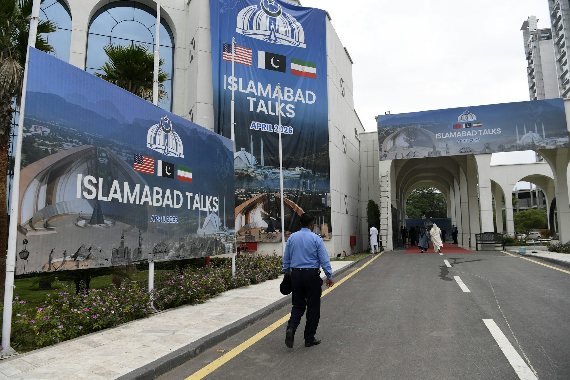 A man walks next to a billboard reading 'Islamabad talks'.