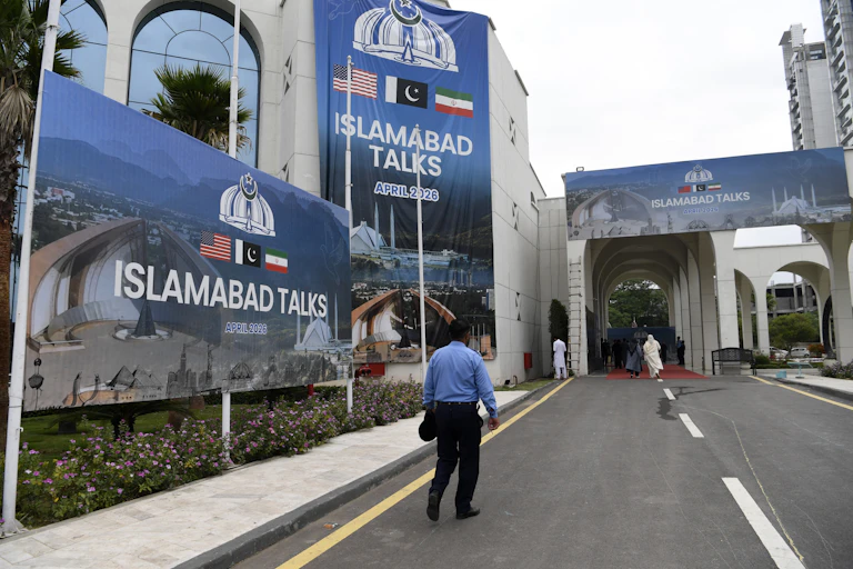 A man walks next to a billboard reading 'Islamabad talks'.