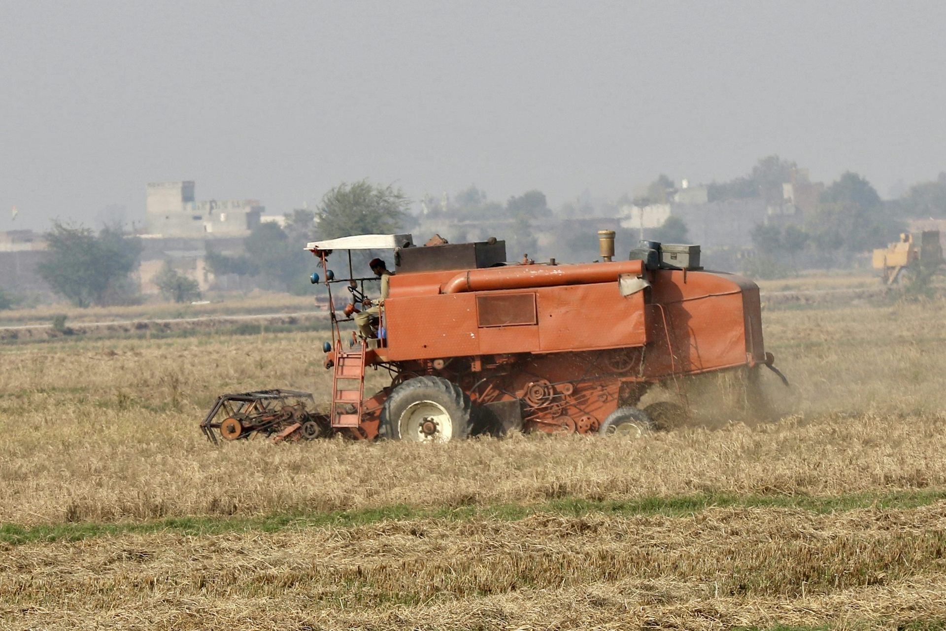 A farmer uses heavy machinery to harvest rice crops in a field on the outskirts of Lahore.