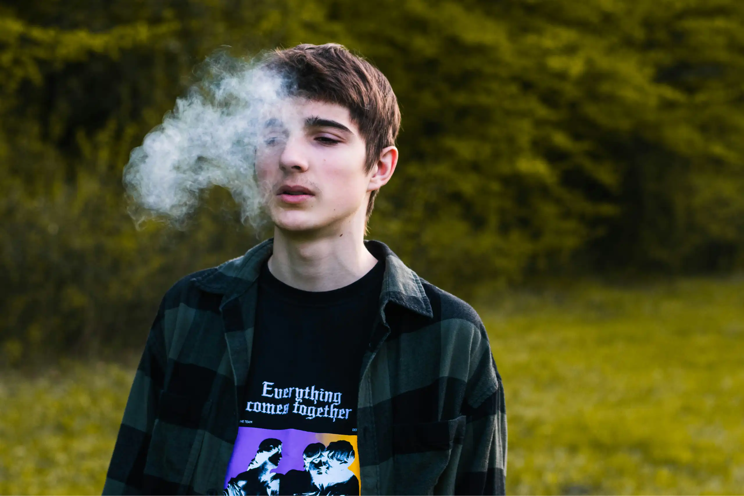 A teenage boy exhales smoke.