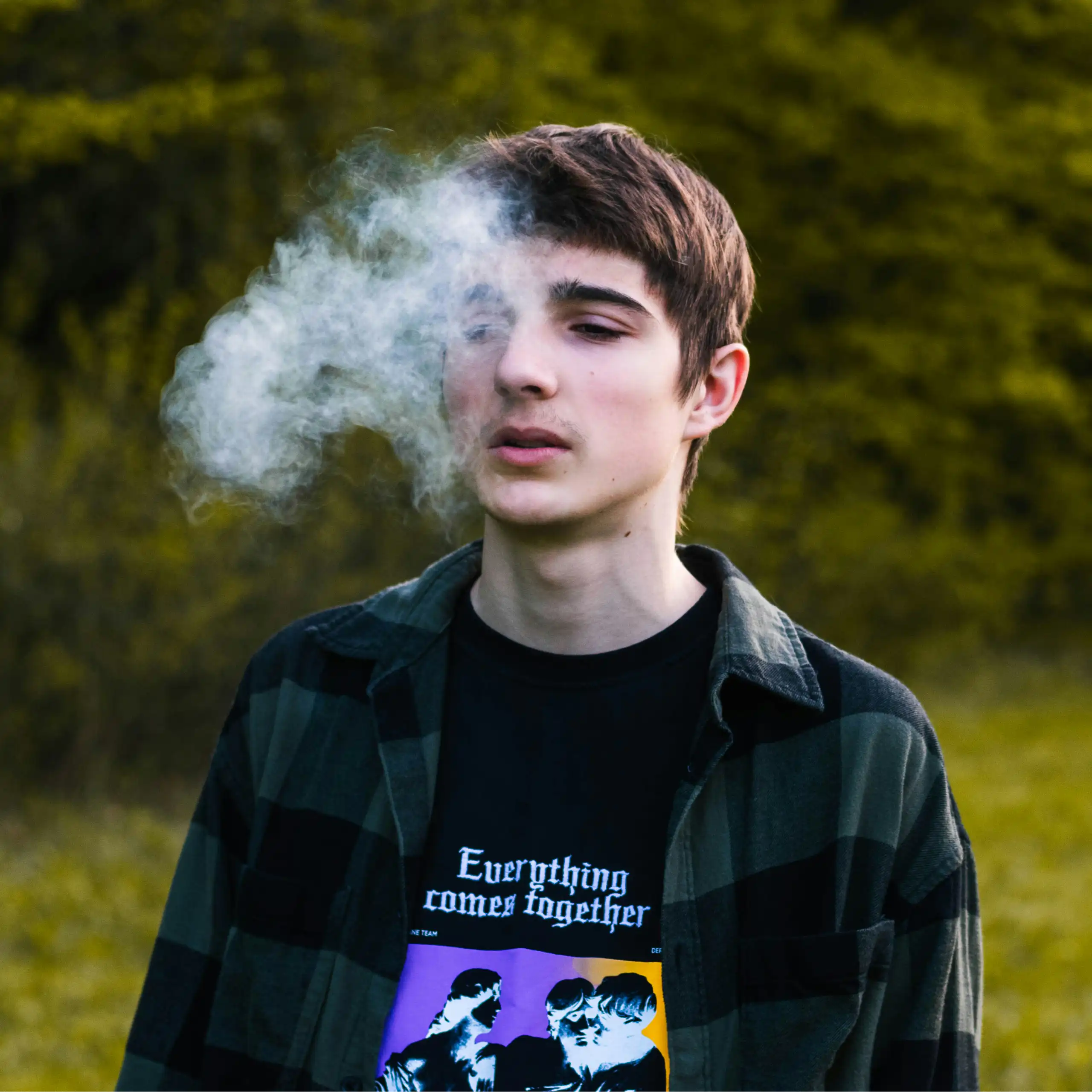 A teenage boy exhales smoke.
