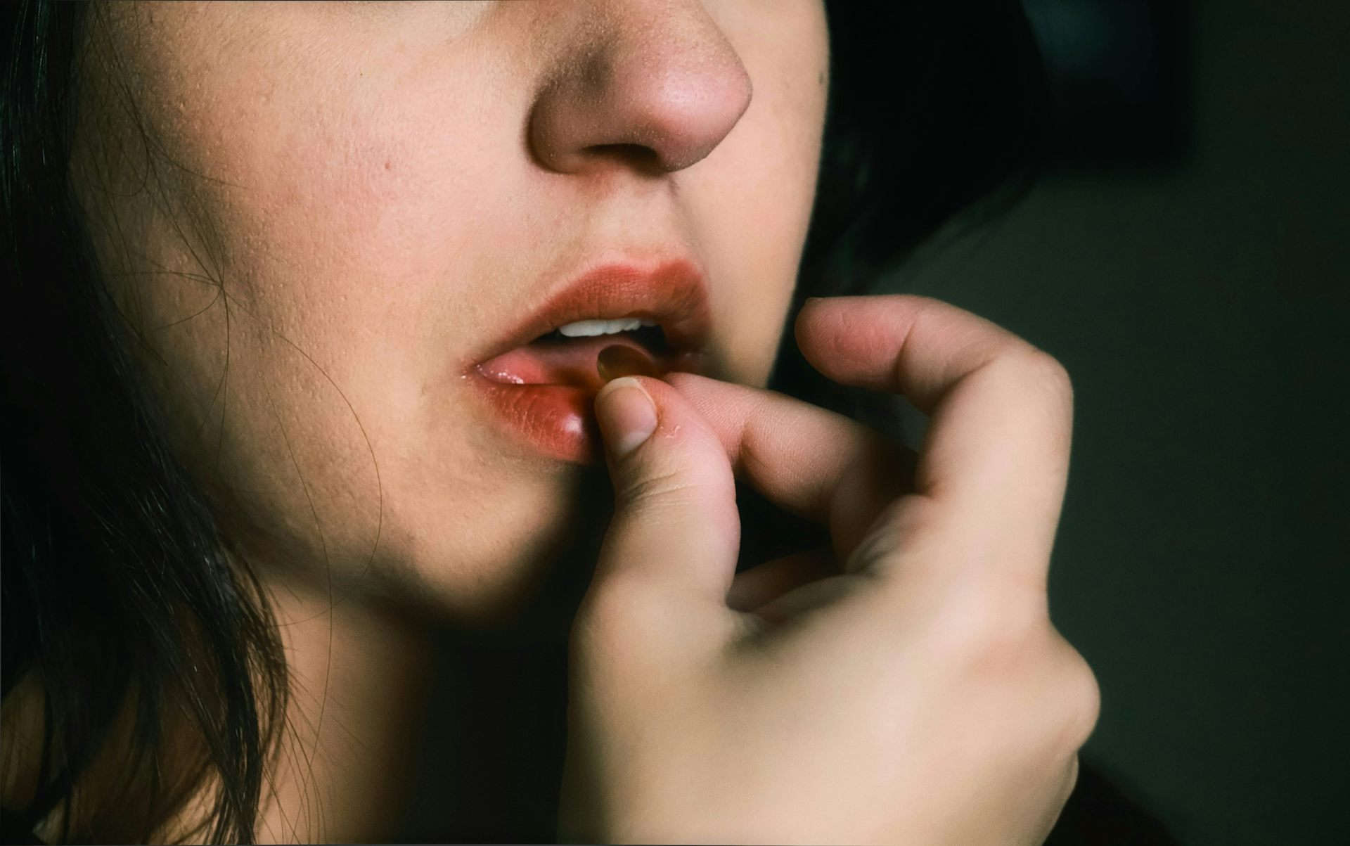 Una adolescente se pone una pastilla en la boca.