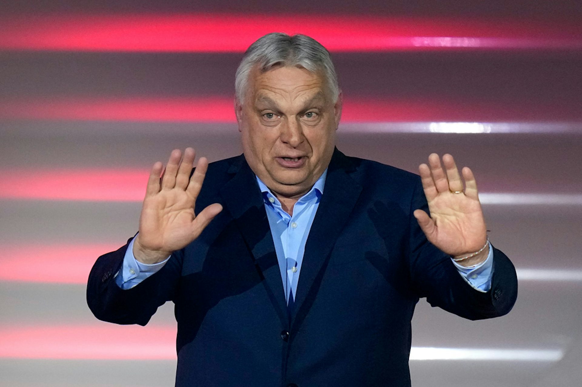 A man in a suit gestures on a stage.