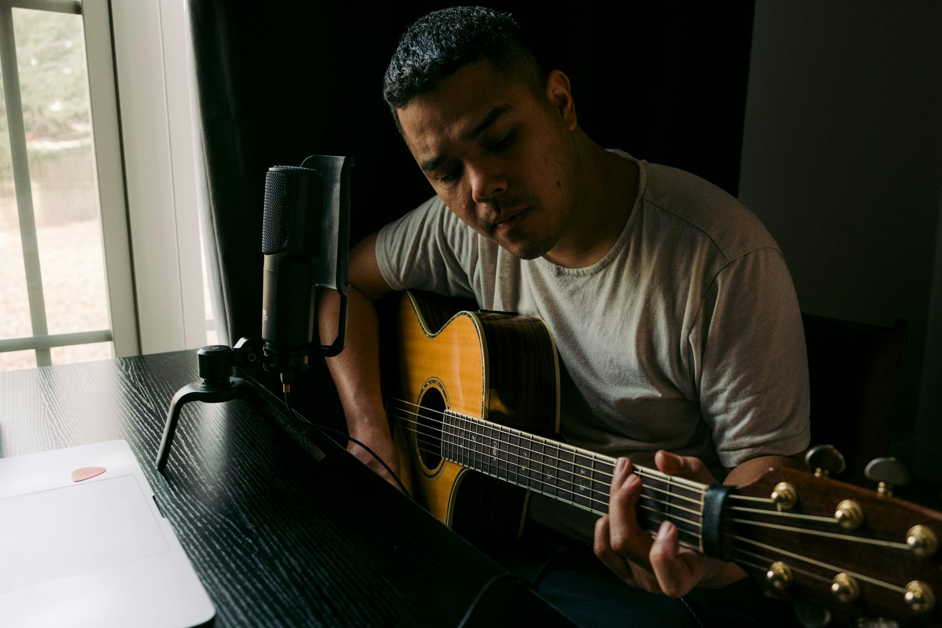 Um homem tocando violão em uma mesa.