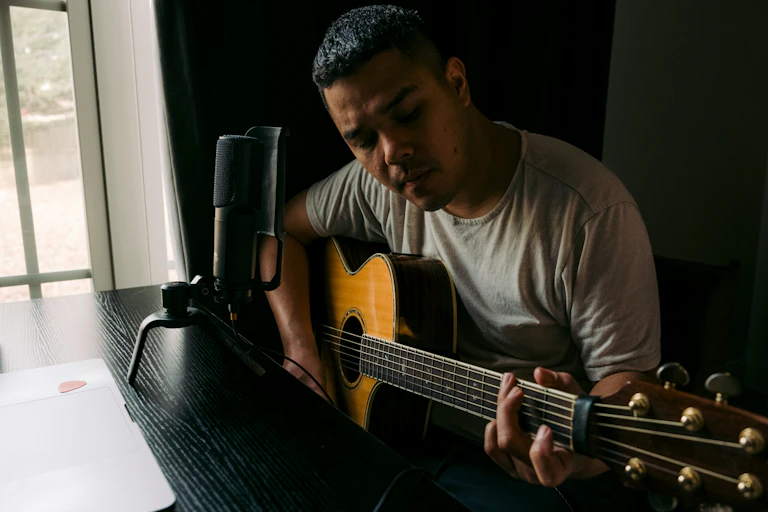 Um homem tocando violão em uma mesa.