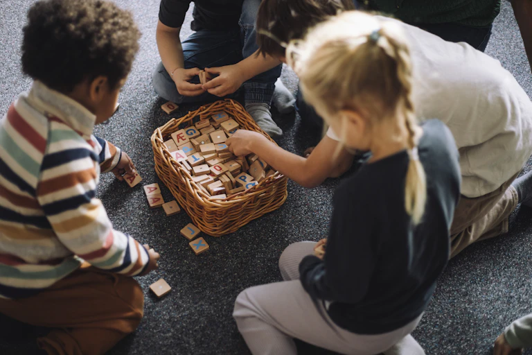 Three children sit on the floor and play with blocks.