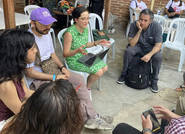 woman in green dress chats to other people sat in chairs in a circle