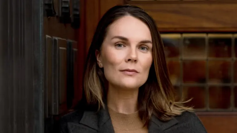 A woman with mid-length brown hair and a blazer