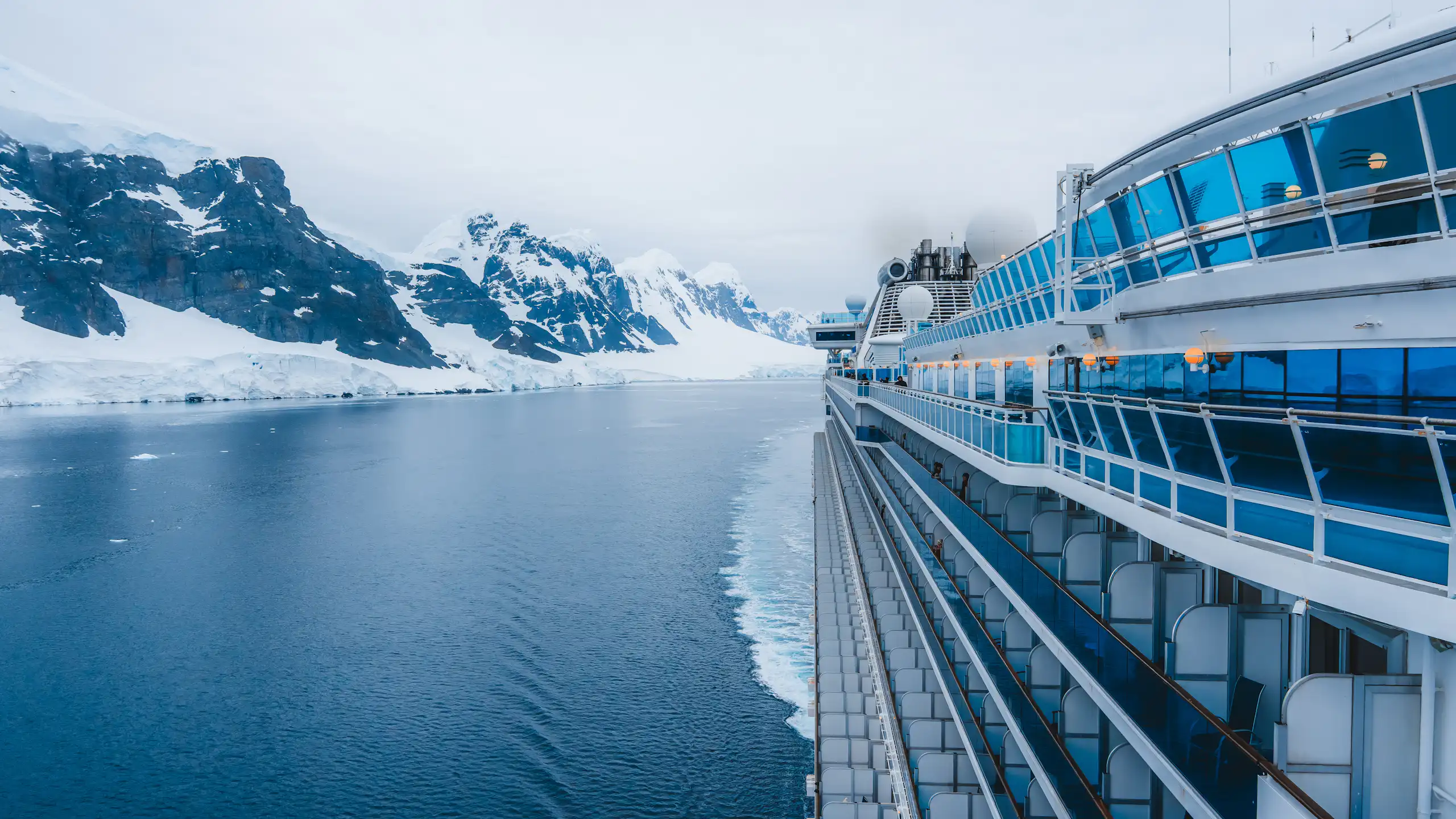 Un creuer bordeja unes muntanyes nevades.