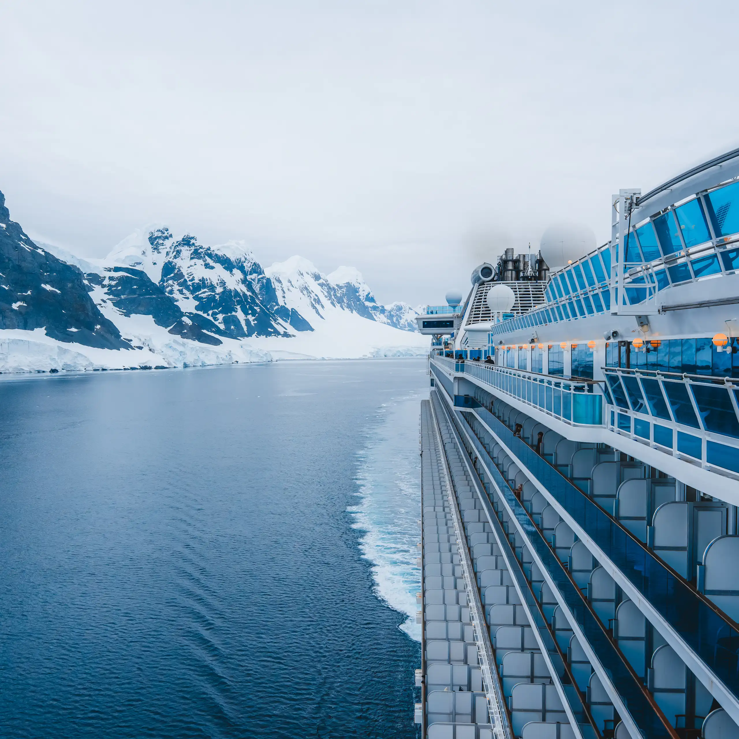 Un creuer bordeja unes muntanyes nevades.