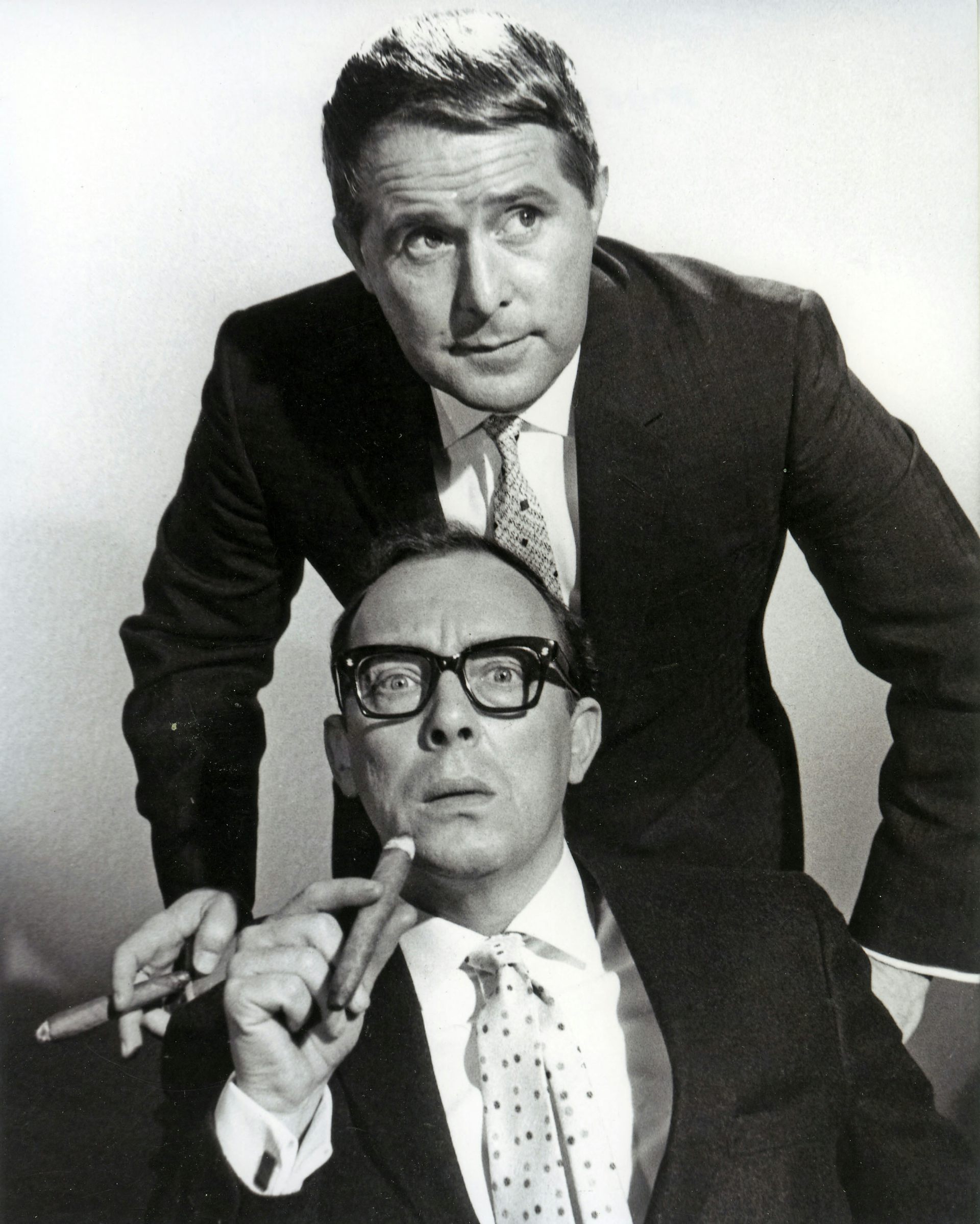 A black and white image of Morecambe and Wise, both holding cigars.
