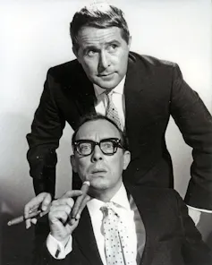 A black and white image of Morecambe and Wise, both holding cigars.