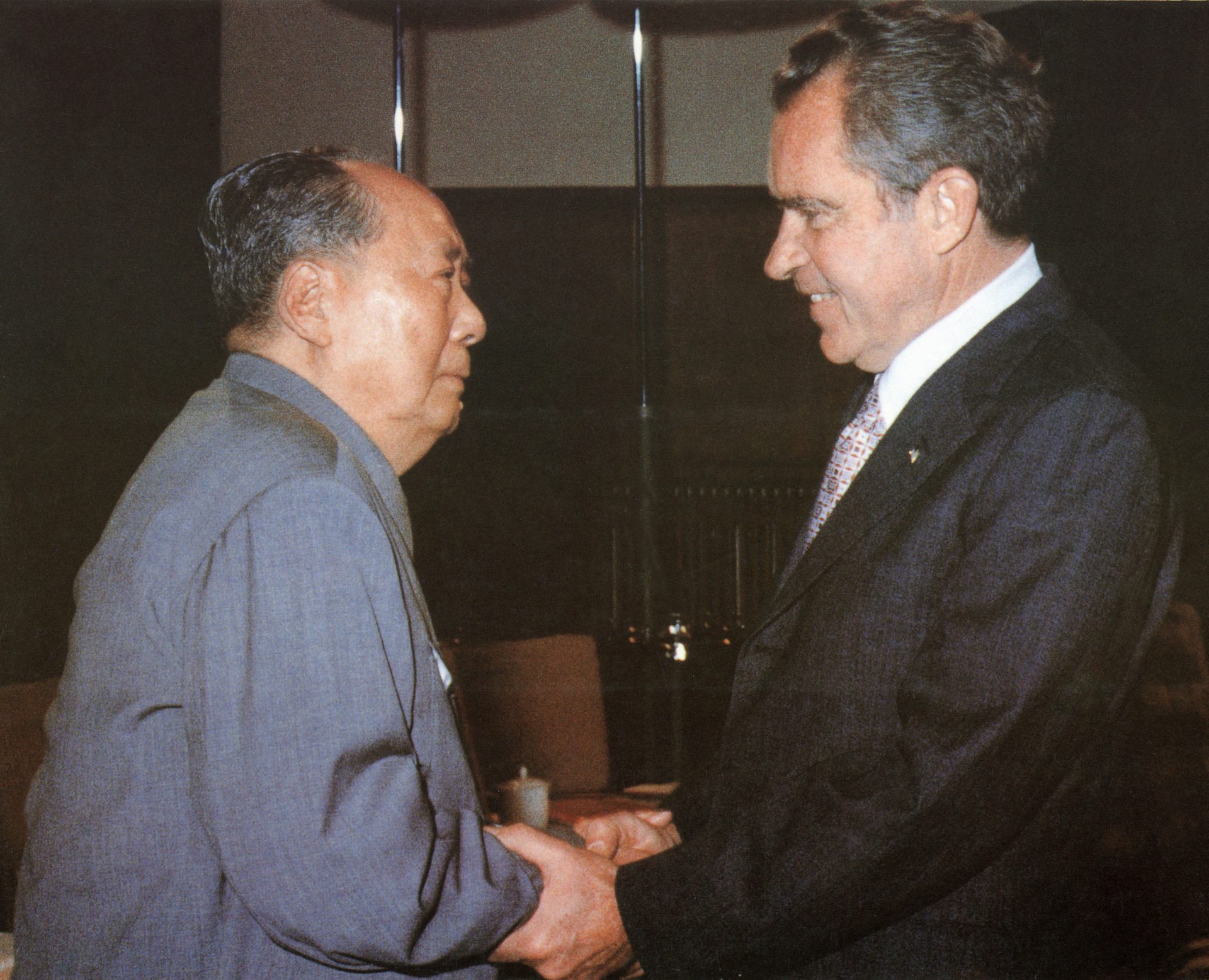 Two men in suits shake hands.