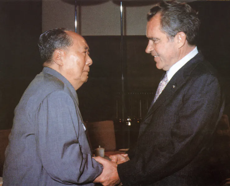 Two men in suits shake hands.