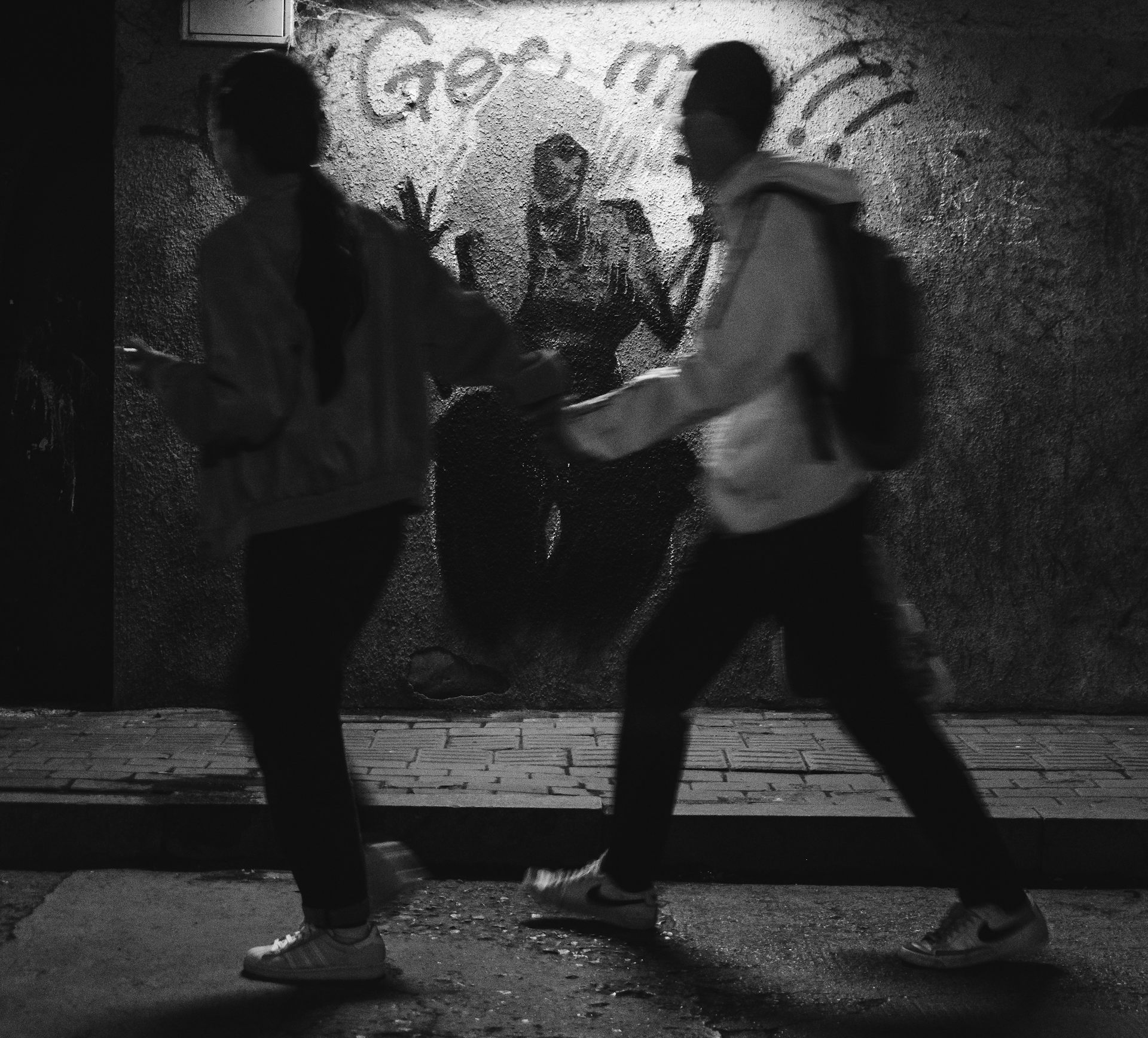 A blurred image of two teenagers in an alley.