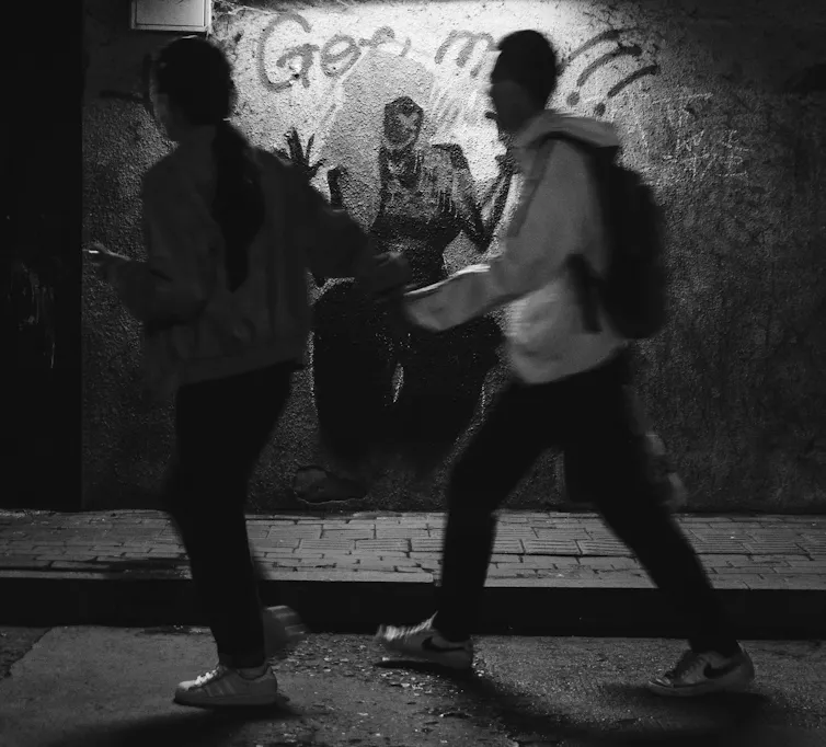 A blurred image of two teenagers in an alley.