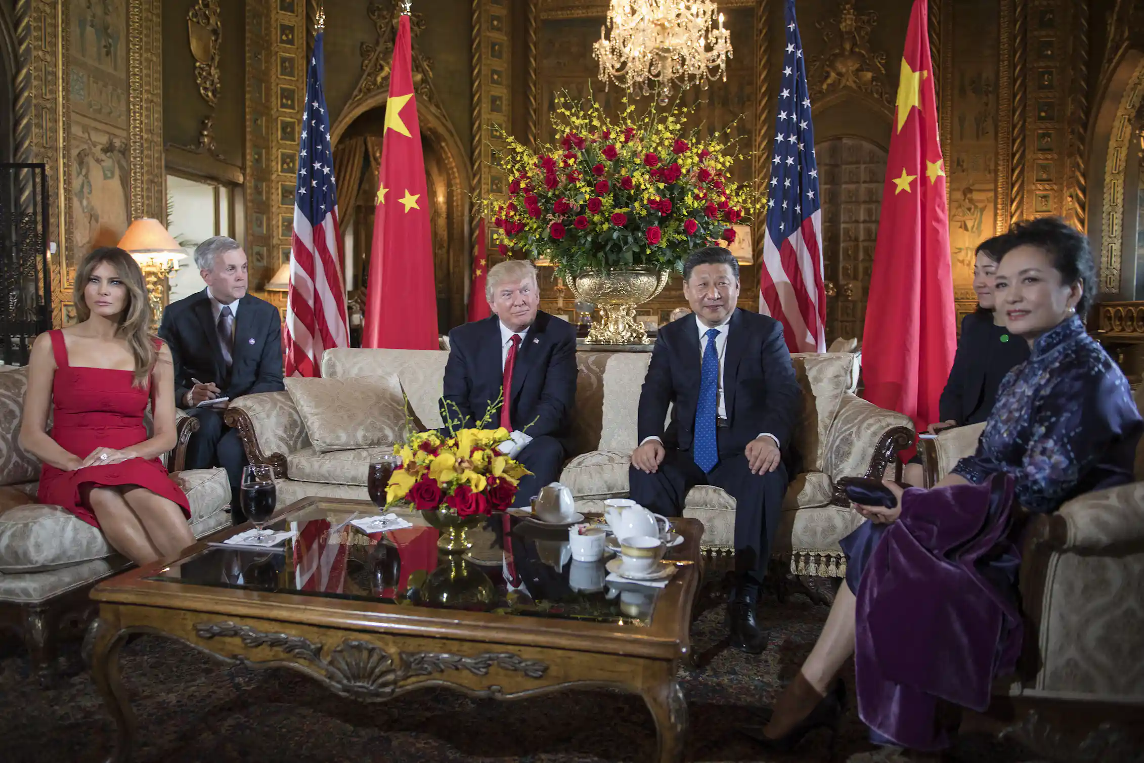Four people sit on chairs surrounded by flags.