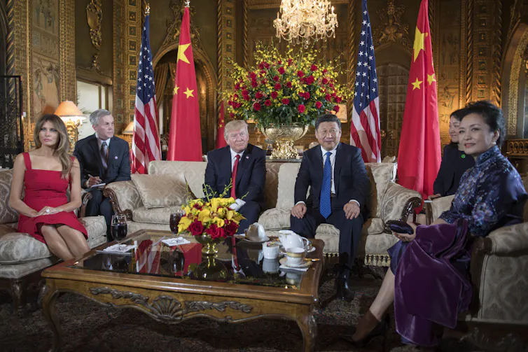 Four people sit on chairs surrounded by flags.