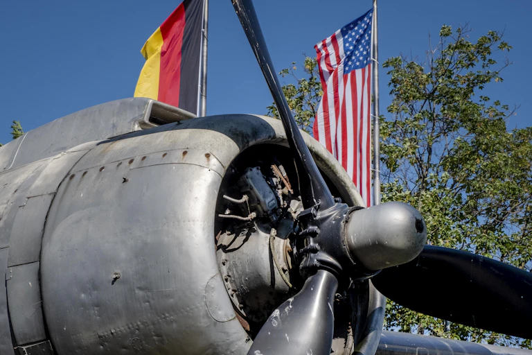 The propeller of a plane is seen in front of the flags of Germany and the U.S.