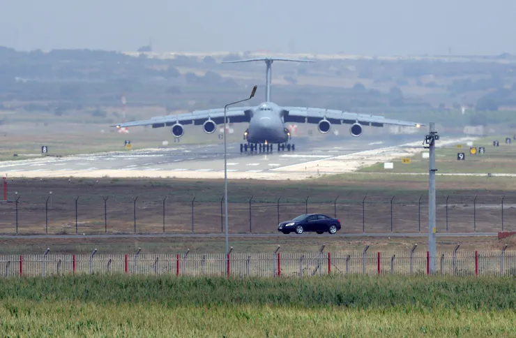 A military plane lands on a runway.