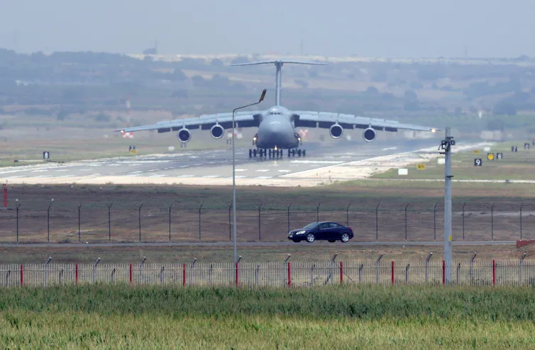 A military plane lands on a runway.