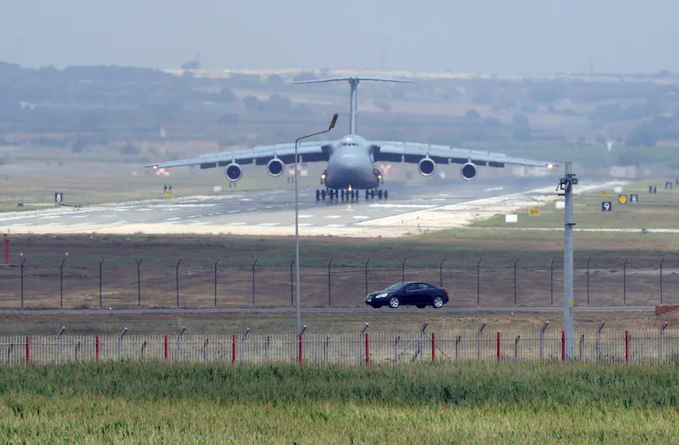 A military plane lands on a runway.