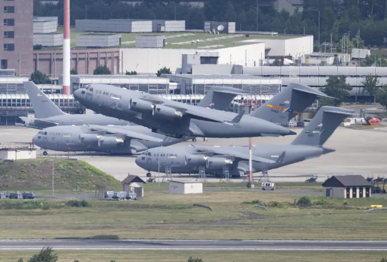 A military transport plane takes off from a runway.