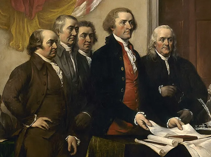 Five men in colonial dress, standing next to a table covered with papers.