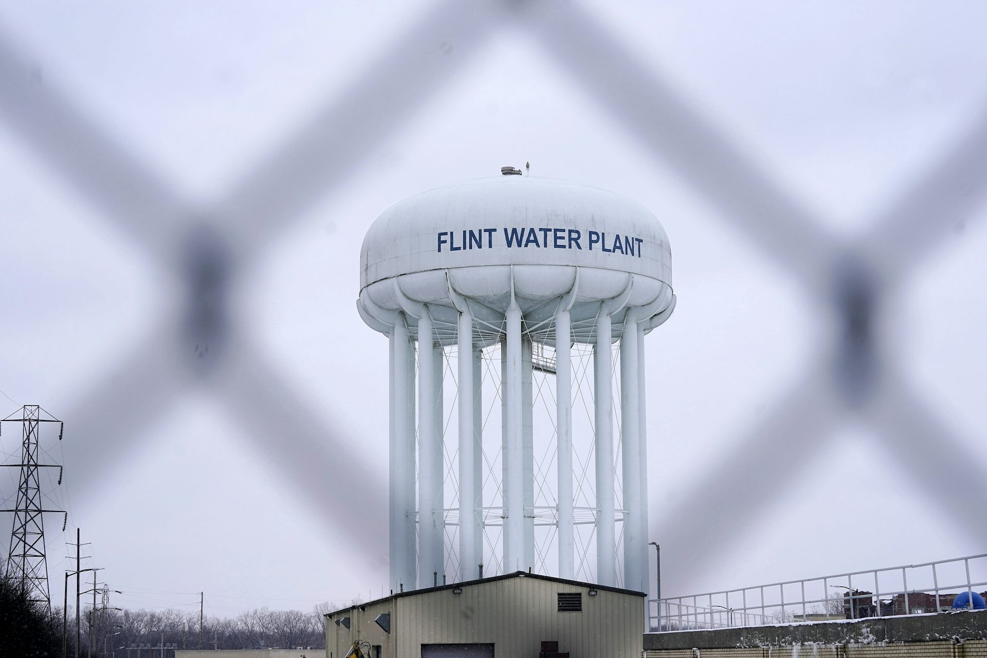 Una torre de agua que lee la planta de agua de Flint fotografiada detrás de una valla metálica.