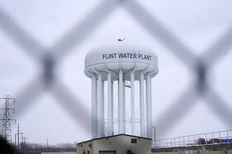 La nueva ley de agua y saneamiento de Ontario podría allanar el camino para la financiación pública del agua 3 Una torre de agua que lee la planta de agua de Flint fotografiada detrás de una valla metálica.