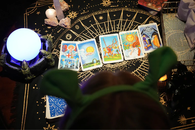 A table with crystals, an orb and colorful cards spread out on the surface.