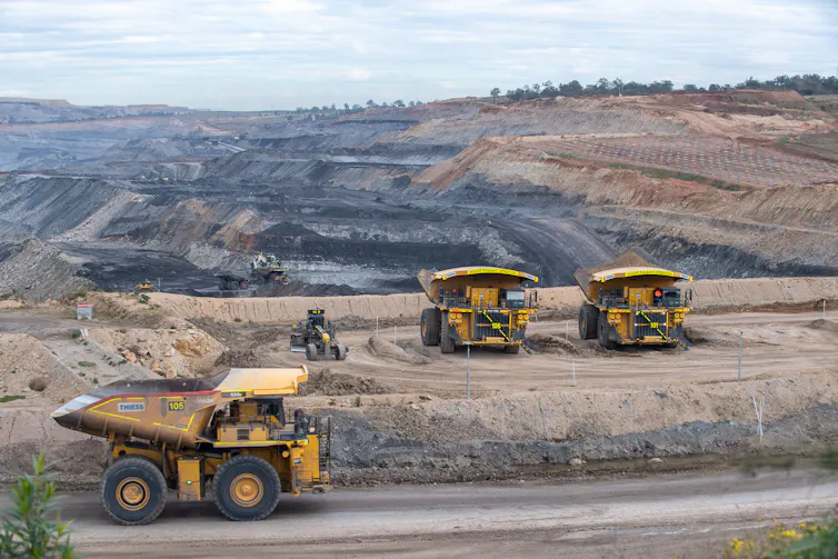 dump trucks in foreground, coal mine behind.