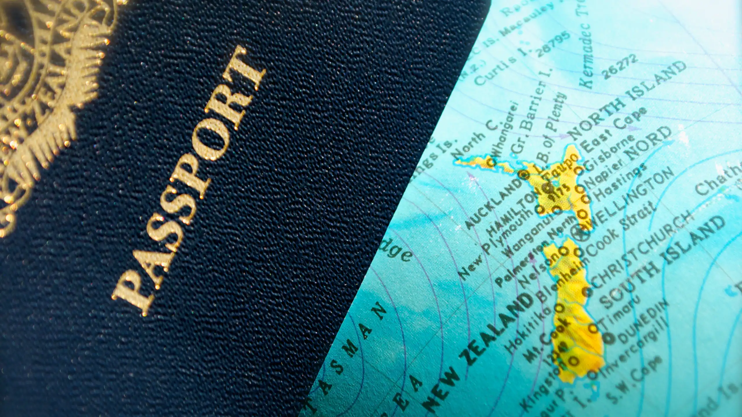 Close-up detail of an NZ passport laid over a portion of a globe showing an NZ map