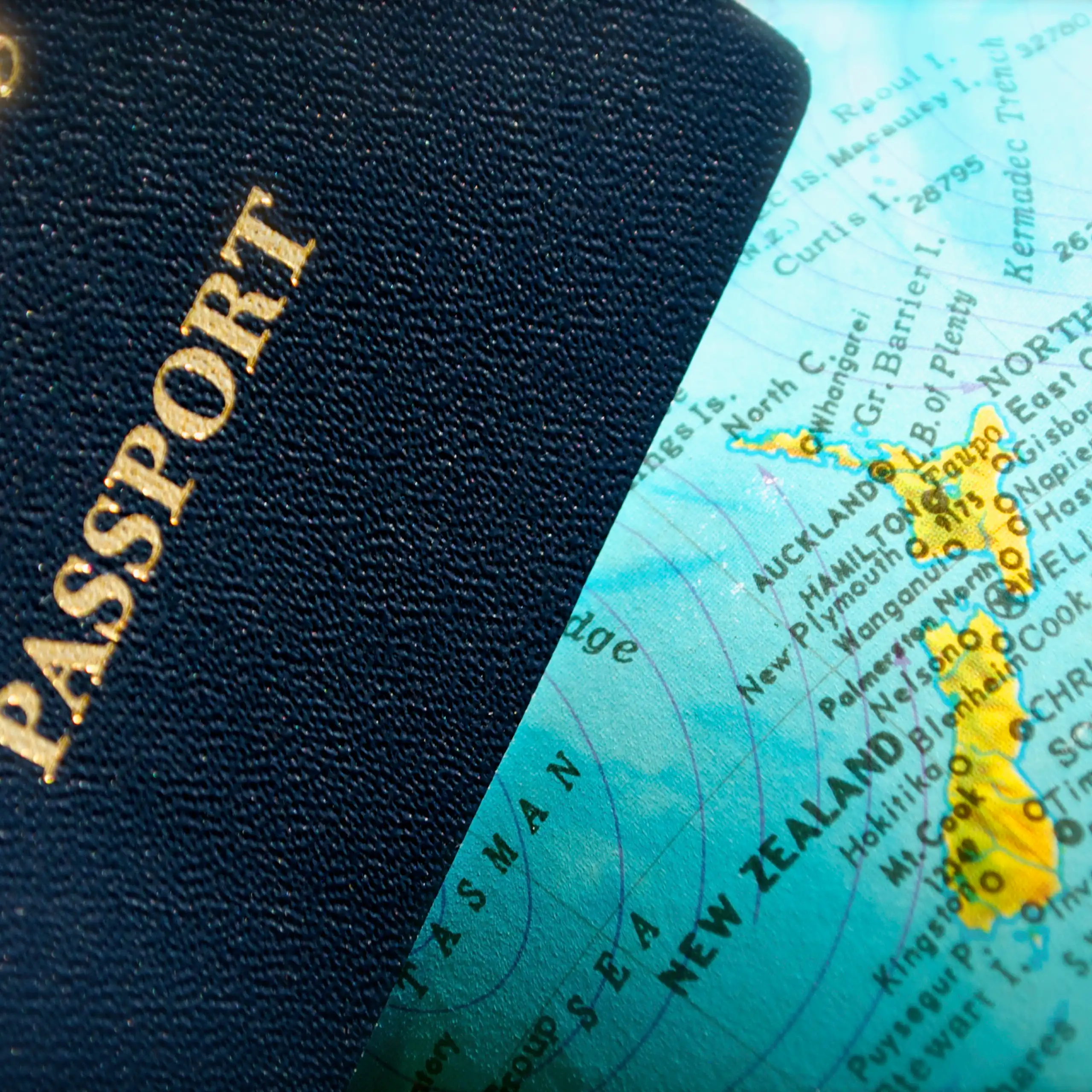 Close-up detail of an NZ passport laid over a portion of a globe showing an NZ map